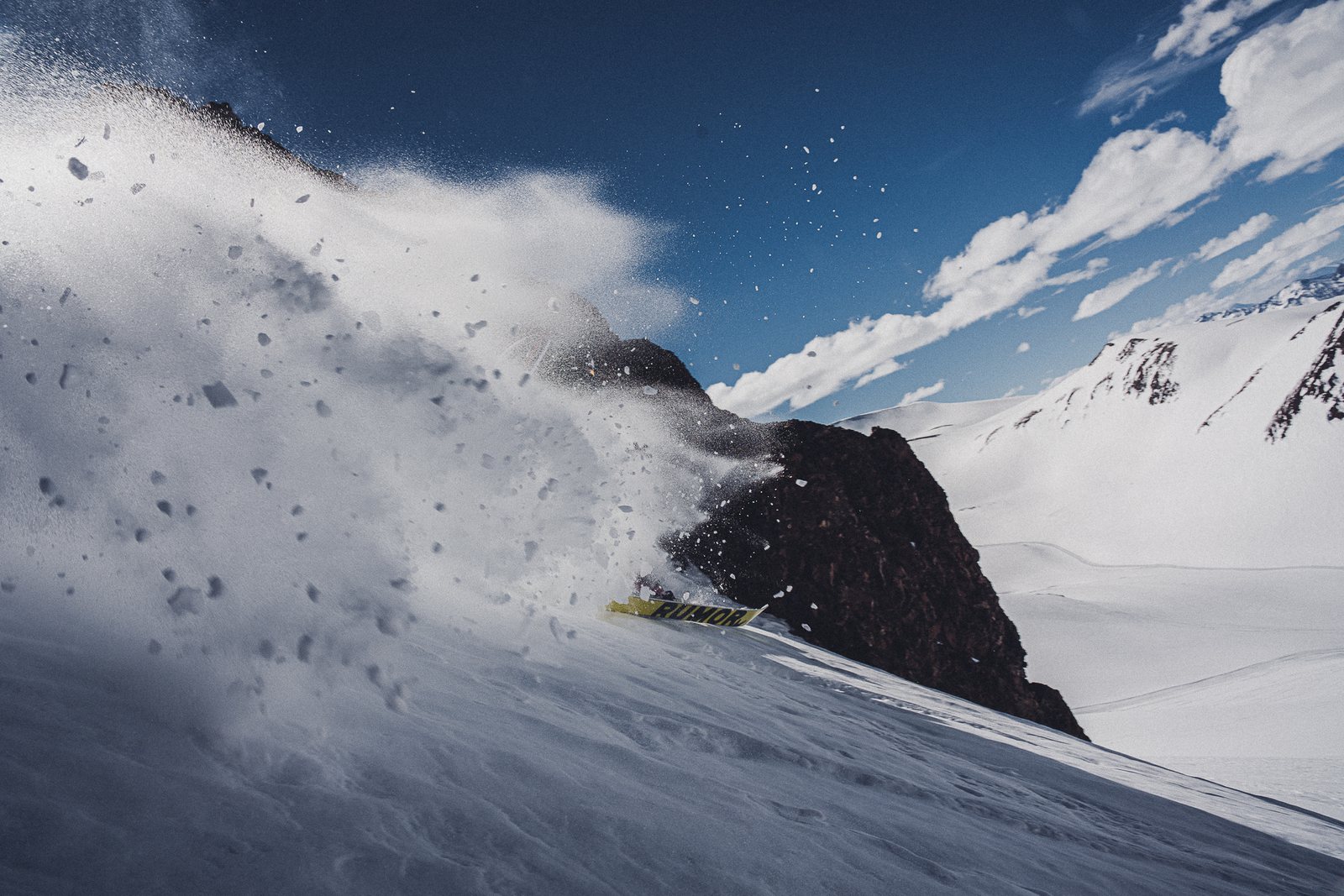 A skier throwing snow off a ridge line